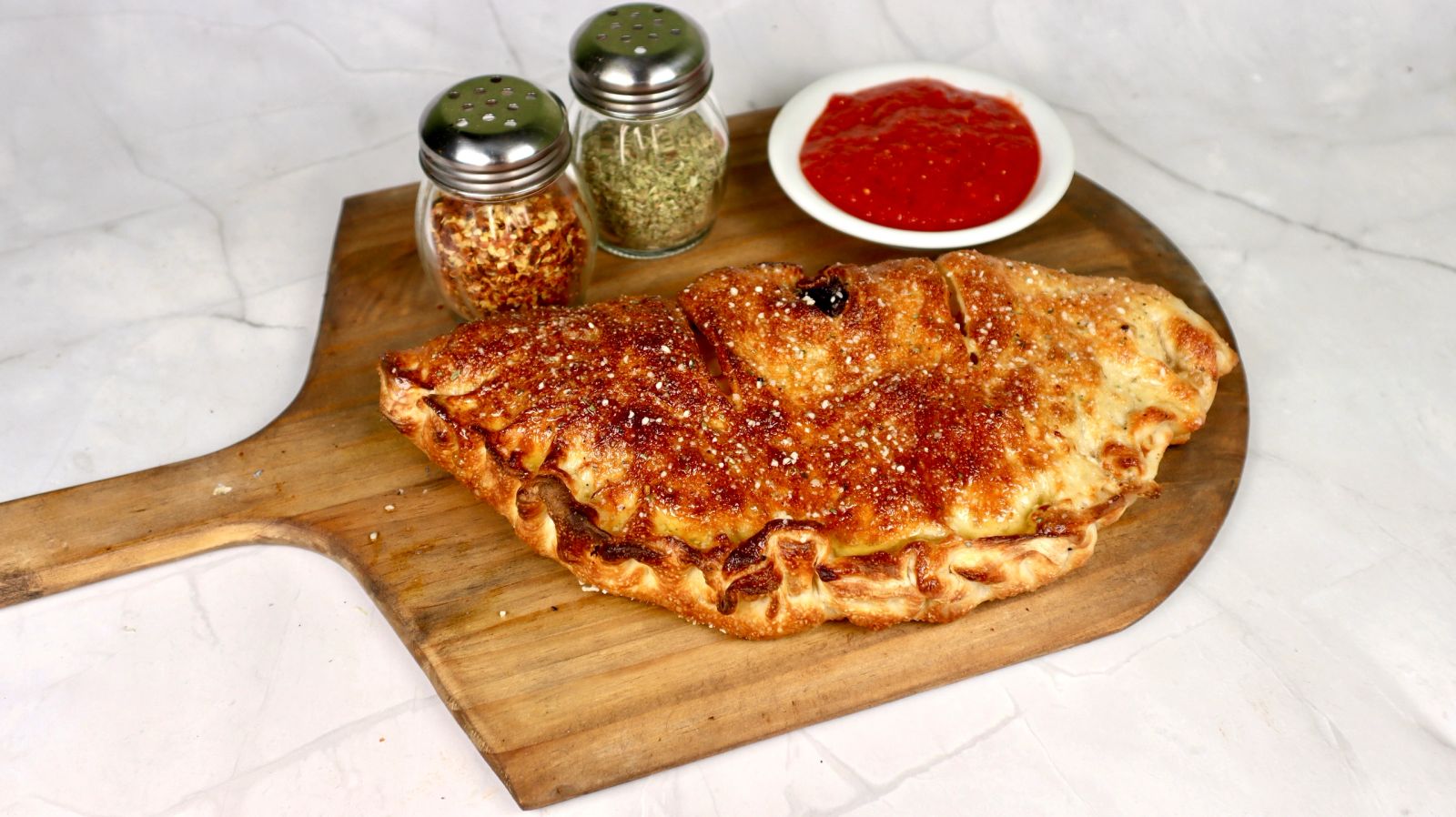 A golden, hand-folded calzone served with house marinara